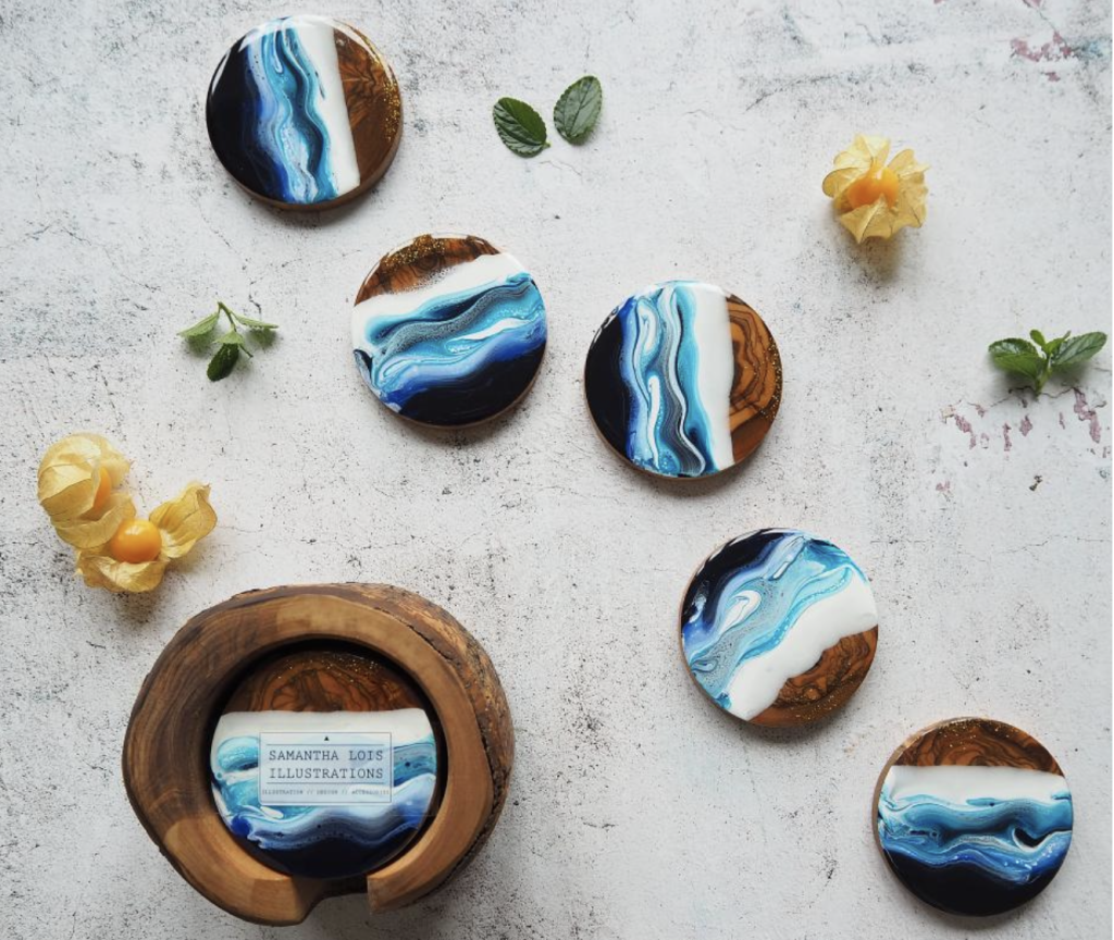 Above: Samantha Lois Illustration’s Ocean Olive Wood Coasters features five individually hand-poured resin coated Olive Wood coasters.